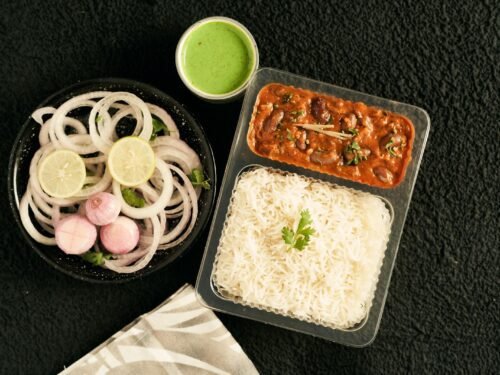 Delicious Indian meal featuring rajma curry, basmati rice, and onion salad with green chutney.