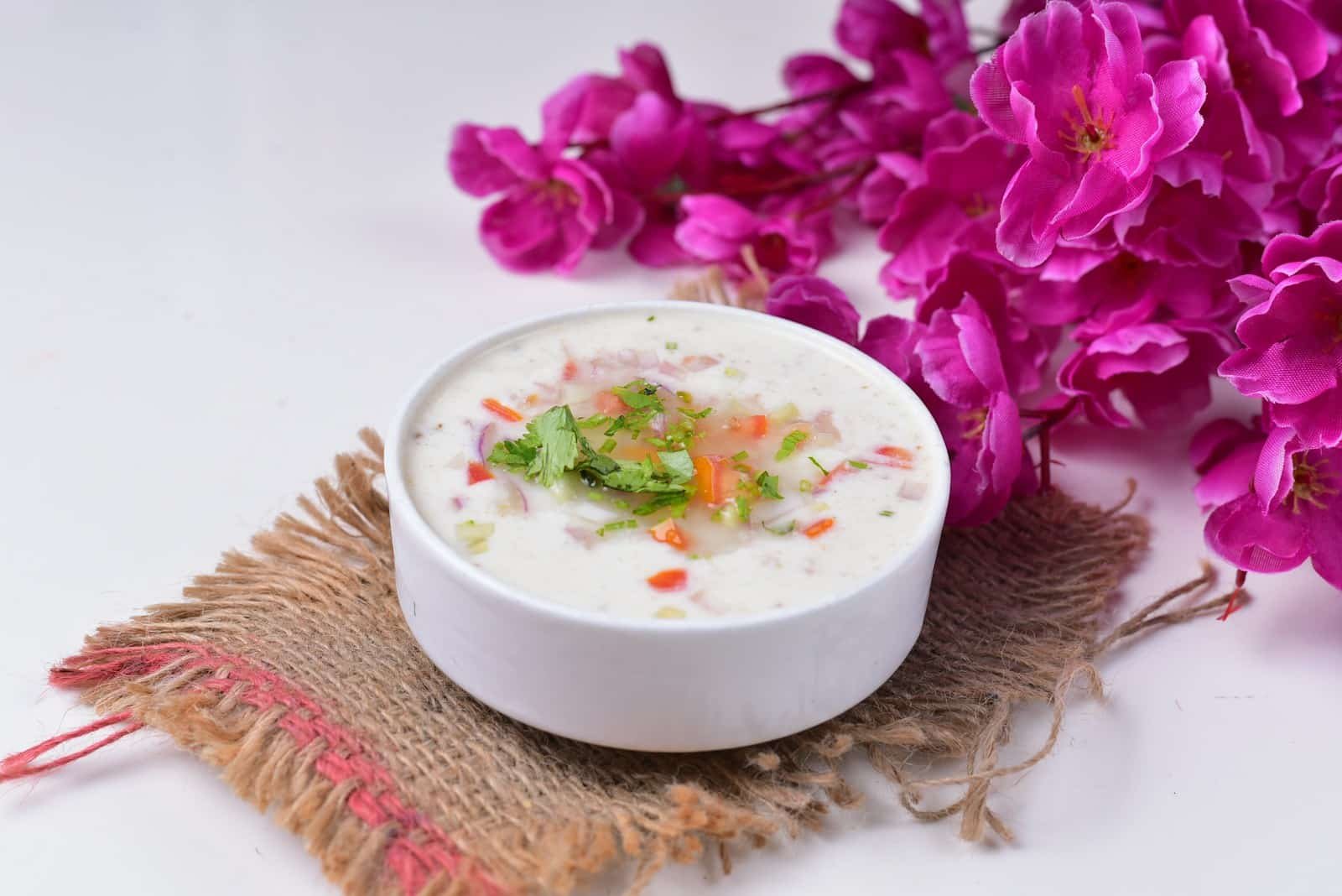 a white bowl filled with soup next to purple flowers